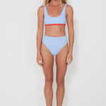 Woman wearing a light blue bikini with red accents on a white background