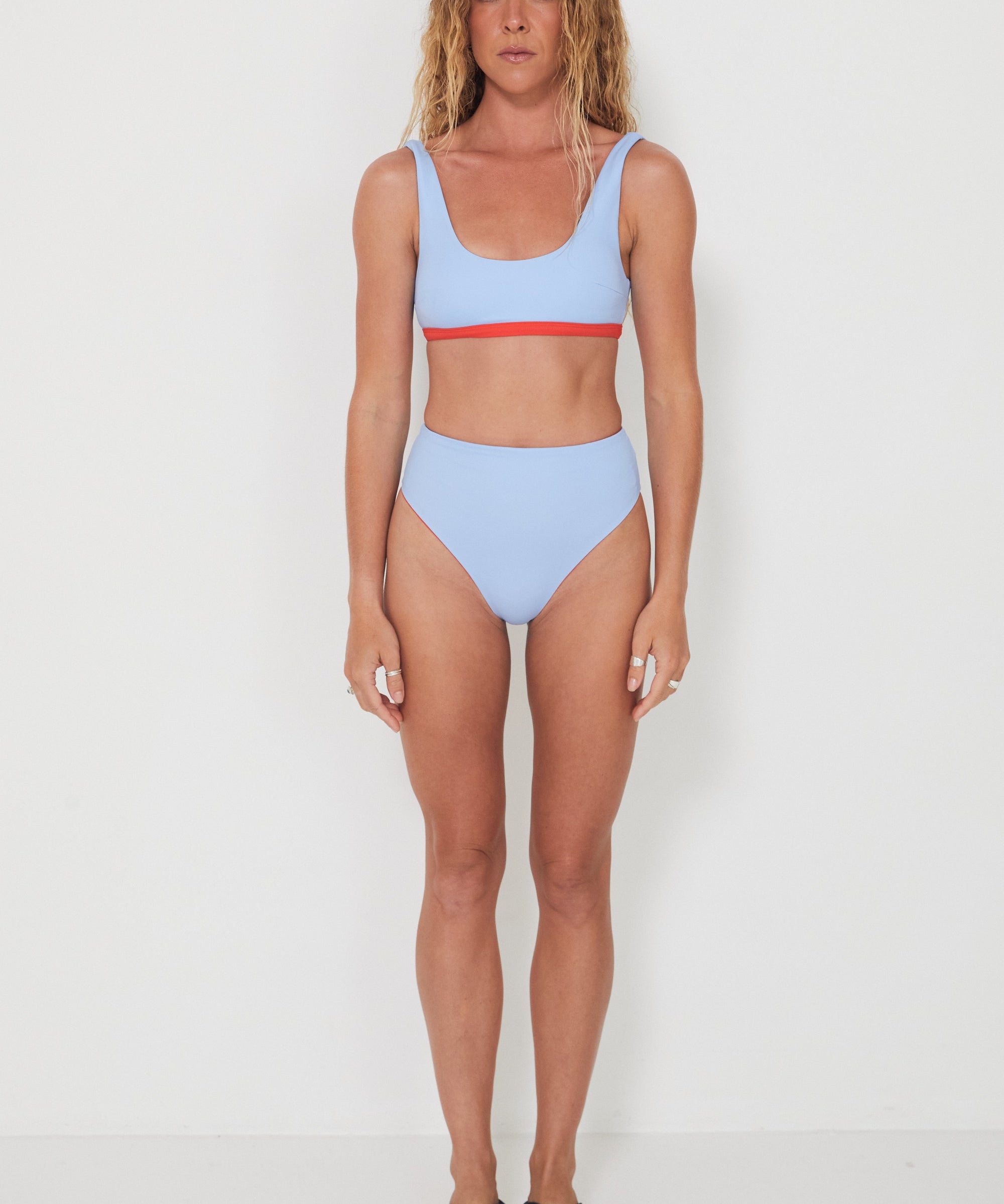 Woman wearing a light blue bikini with red accents on a white background