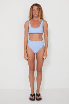 Woman wearing a light blue bikini with red accents on a white background