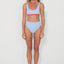 Woman wearing a light blue bikini with red accents on a white background