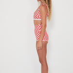 Woman wearing a red and white checkered bralette swim top and original betty bottoms on a white background