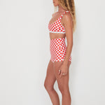 Woman wearing a red and white checkered swim set against a white background