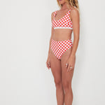 Woman wearing a red and white checkered bikini set on a white background