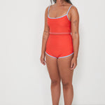 Woman wearing a red two piece swim set with blue trim on a white background