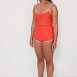 Woman wearing a red two piece swim set with blue trim on a white background