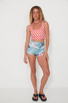 Woman wearing a red and white checkered punchy surf top and patterned original betty bottoms shorts on a white background
