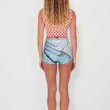 Person wearing a red and white checkered top and blue shorts with a graphic design on a white background