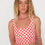Woman wearing a red and white checkered punchy surf crop top against a white background