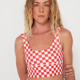 Woman wearing a red and white checkered punchy surf crop top against a white background
