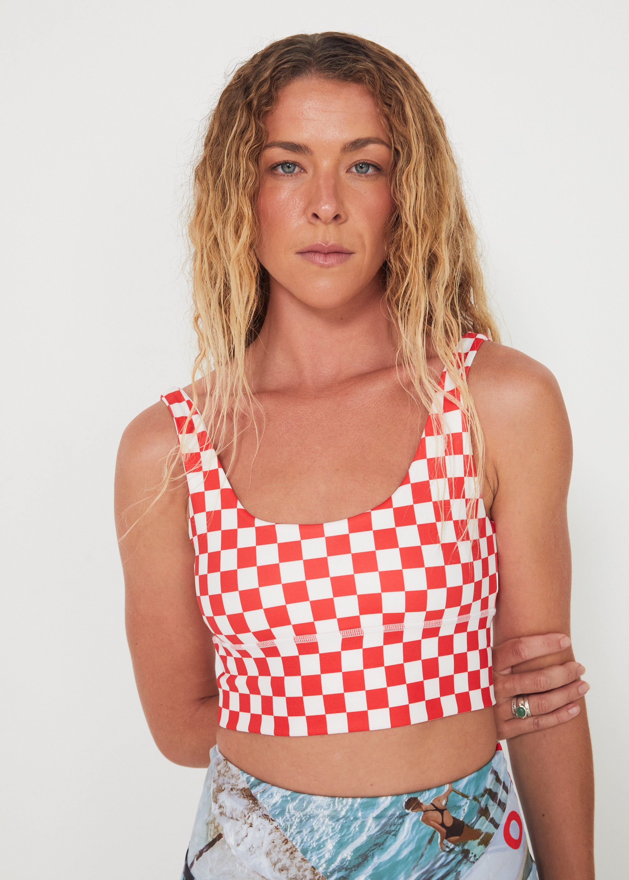 Woman wearing a red and white checkered punchy surf crop top against a white background