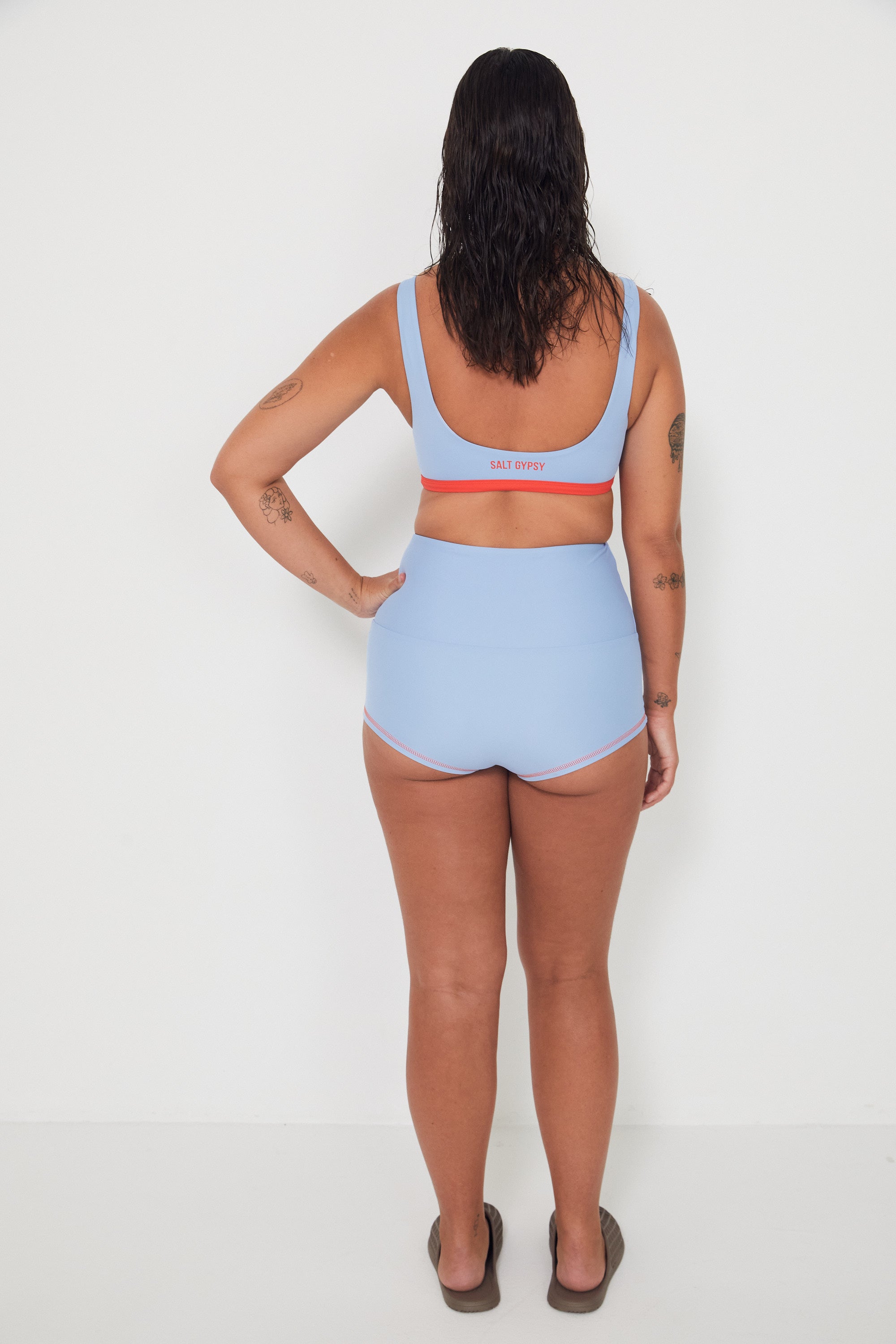 Person wearing a light blue sports bralette surf top bra and high-waisted original betty bottoms swim bottoms on a white background