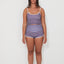 Woman wearing a merlot striped tankini surf top and betty bottom 2.0 shorts set on a white background