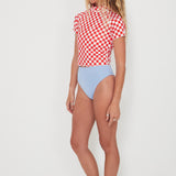 Woman wearing a red and white checkered rashguard and light blue high-waisted bottoms on a white background