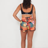Woman wearing a black and white bralette sports swimwear bra and colorful floral and vacay print boardshorts by salt gypsy and friday on a white background