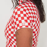 Person wearing a red and white checkered rashguard with a visible brand logo on a white background
