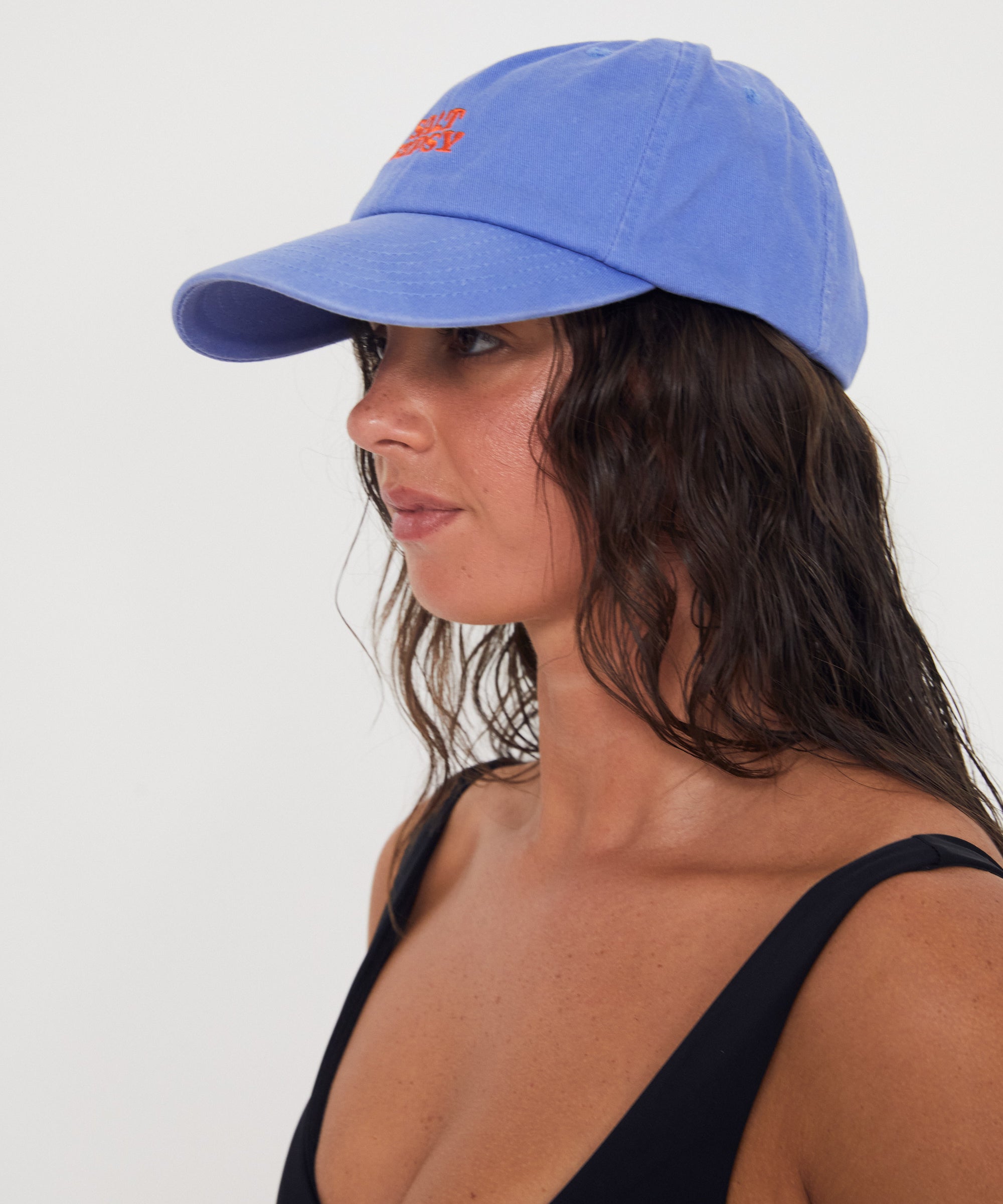 Woman wearing a blue dad cap with red writing on a white background