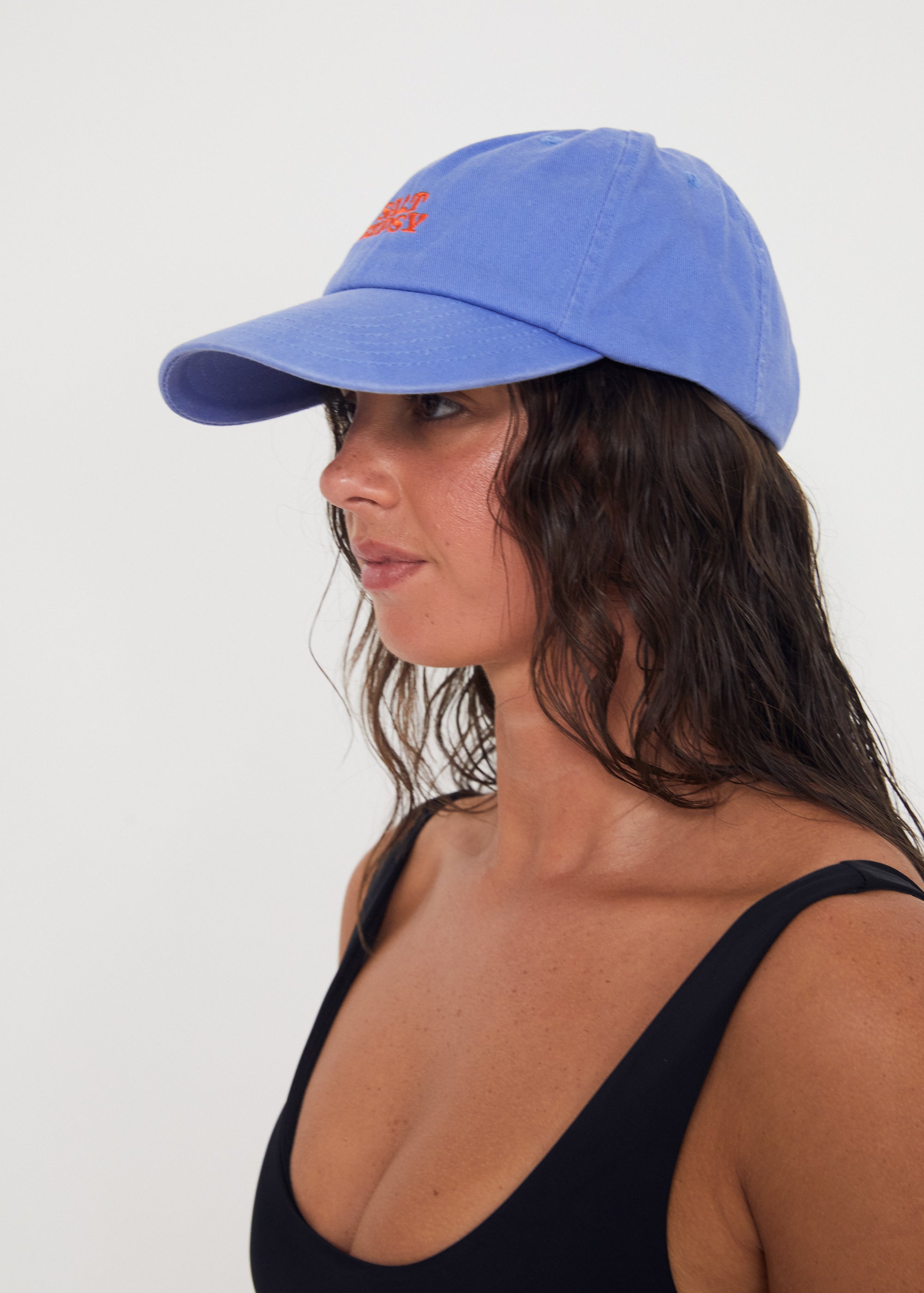 Woman wearing a blue dad cap with red writing on a white background
