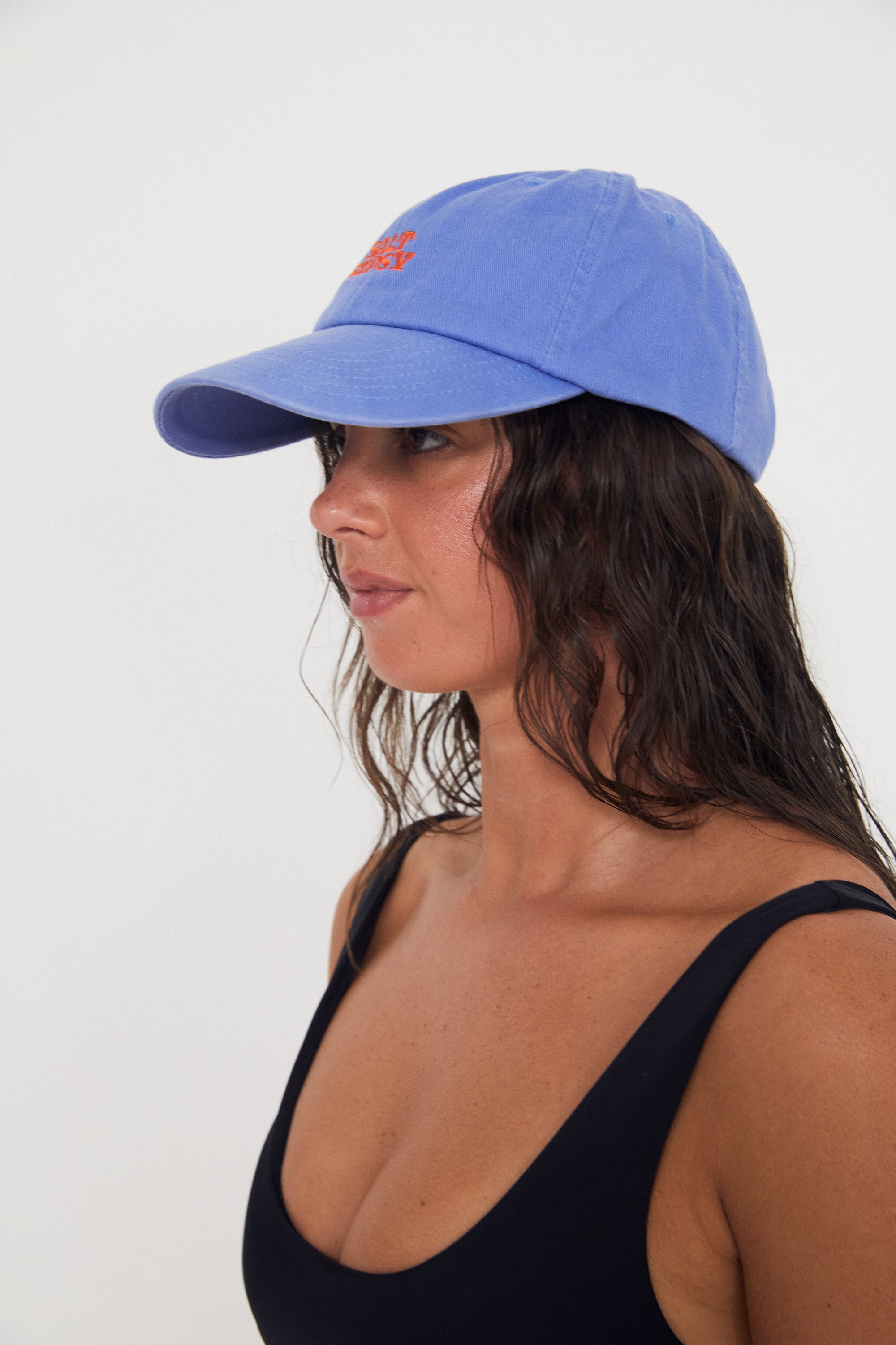 Woman wearing a blue dad cap with red writing on a white background