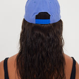 Person wearing a blue dad cap from behind on a white background