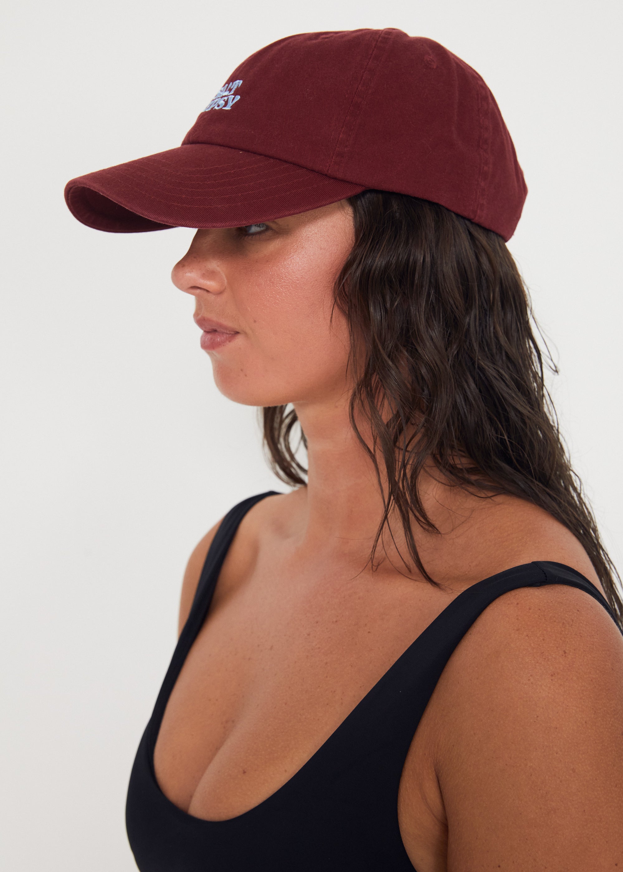 Woman wearing a maroon baseball dad cap on a white background