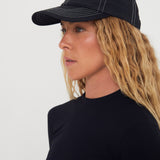 Woman wearing a black nylon cap with a logo on a white background