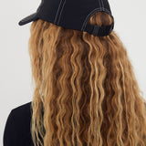 Person wearing a black nylon cap with long wavy hair on a white background