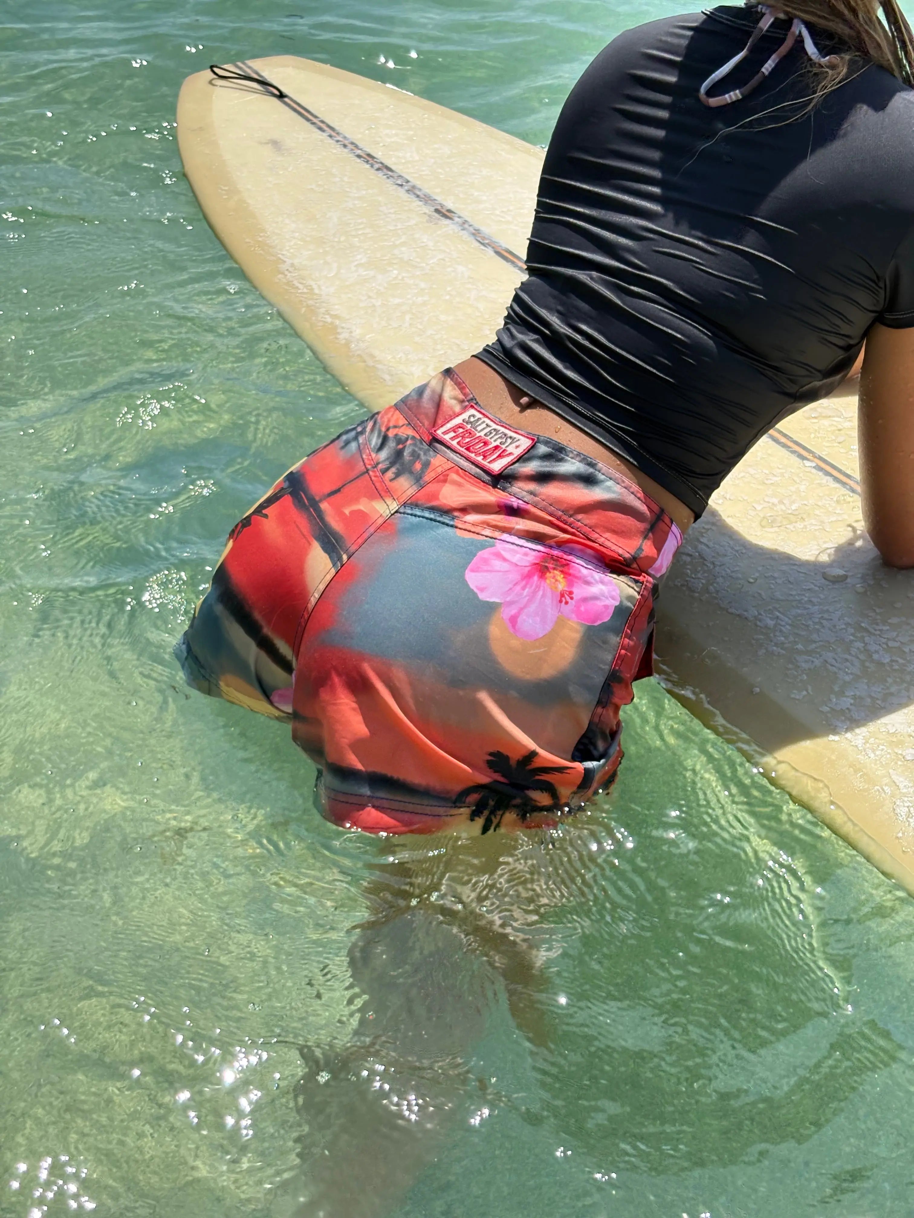 Woman wearing Brand Friday x Salt Gypsy collab boardshorts in vacay print in the water