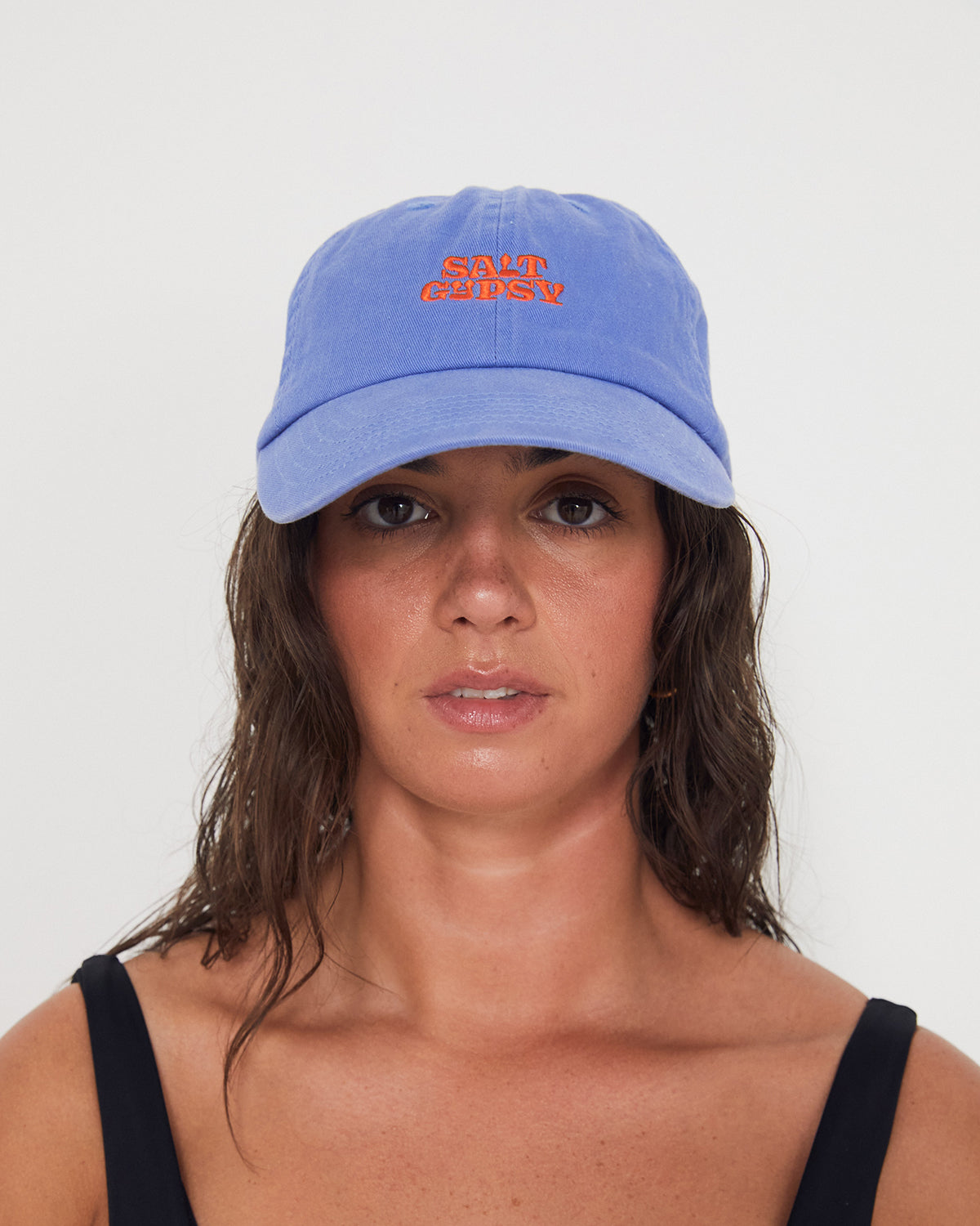 Woman wearing a blue dad cap with a red 'Salt Gypsy' logo on a white background