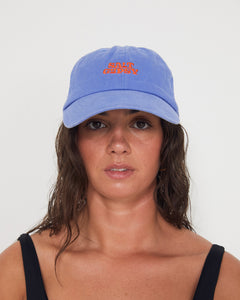 Woman wearing a blue dad cap with a red 'Salt Gypsy' logo on a white background