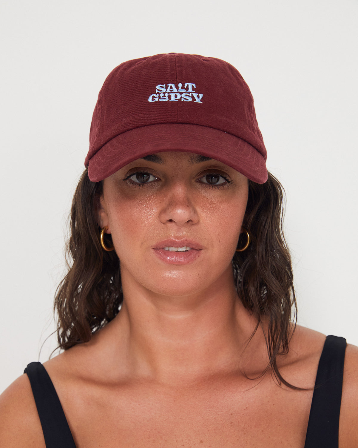 Woman wearing a maroon cap with a blue 'Salt Gypsy' logo on a white background